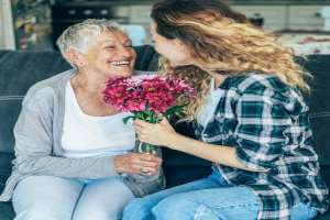 الاحتفال بعيد الأم أثناء جائحة فيروس كورونا المستجد covid 19 - home-style young woman giving flowers to grandmother 1588709101 1 - الاحتفال بعيد الأم أثناء جائحة فيروس كورونا المستجد covid 19
