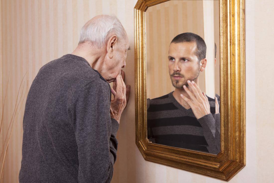 old man looking at younger reflection - أفضل 9 نصائح لتبدو أصغر من عمرك ولتأخير الشيخوخة