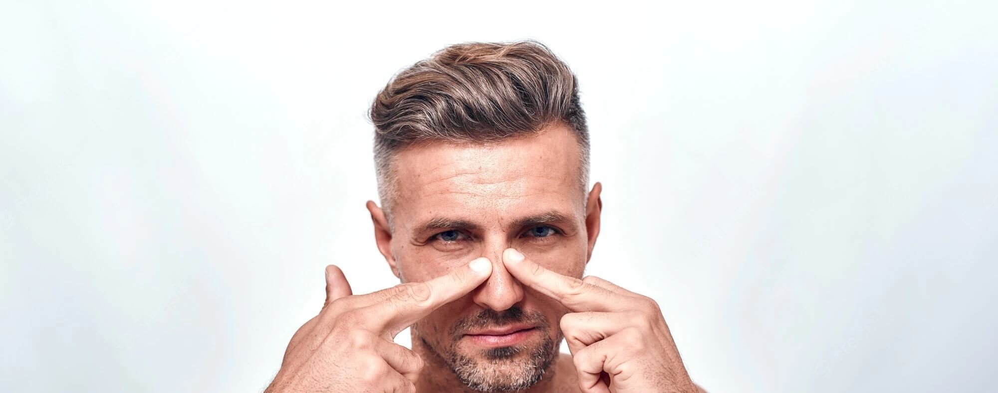 Comment réduire la peau épaisse sur le nez tout devrait être parfait homme inquiet avec chaume examinant son nez regardant la caméra tout en se tenant sur fond gris visage humain tourné en studio rhinoplastie 386167 10598 - Comment réduire la peau épaisse sur le nez