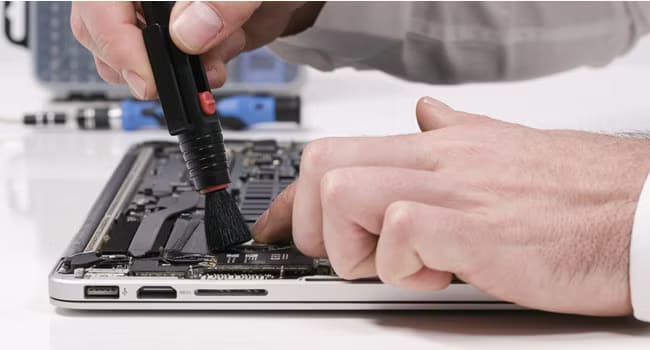 Person-brushing-dust-out-of-a-laptops-ports أفضل طرق تنظيف جهاز Microsoft Surface والحفاظ عليه في حالة ممتازة