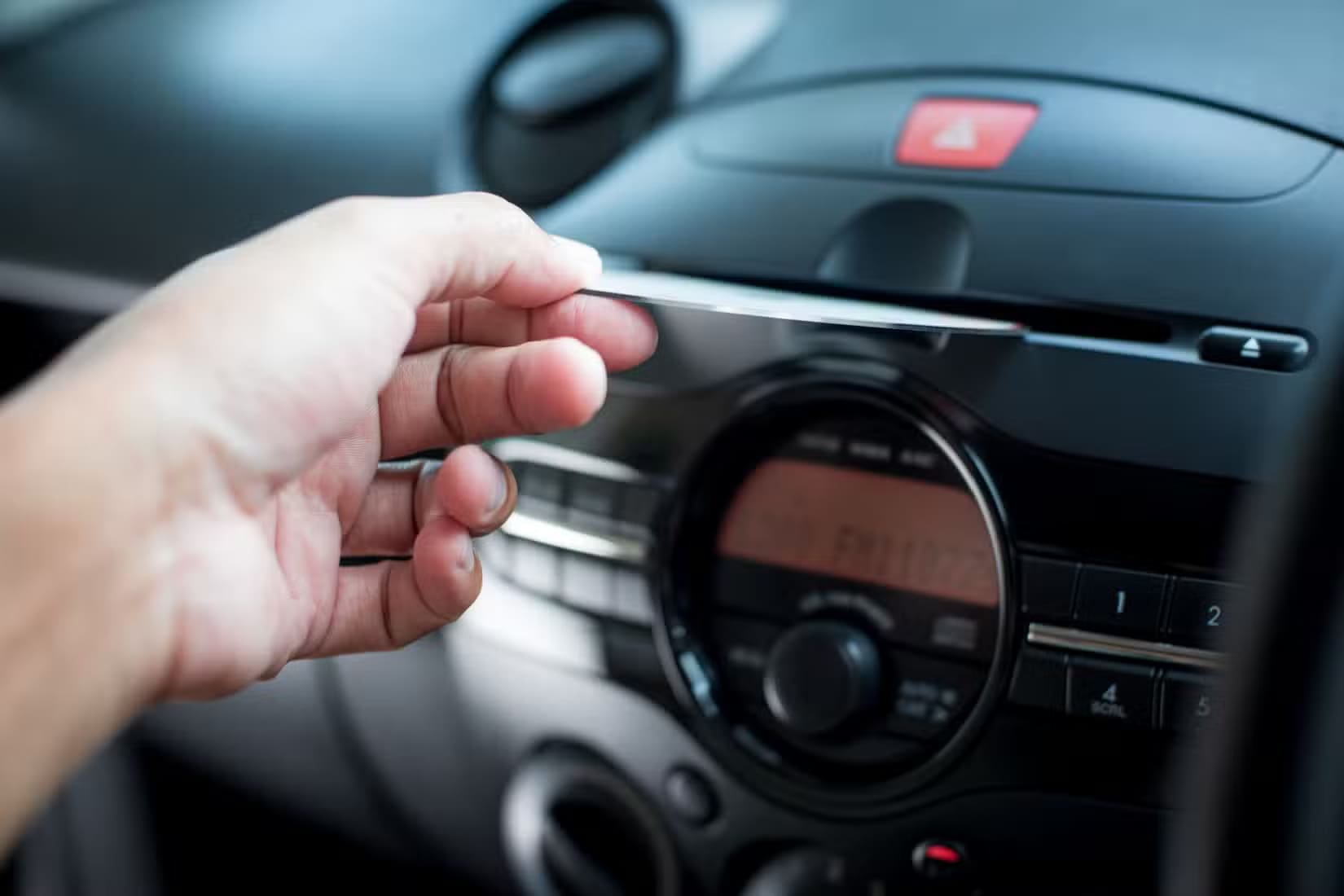 the-man-inserting-cd-to-cd-player-in-the-car أسرار ضغط الصوت وتأثيره على جودة الموسيقى