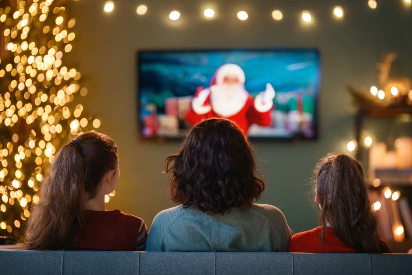 family-sitting-in-front-of-the-tv-at-christmas-1-1 طريقة إعداد Apple Family Sharing وكيفية الاستفادة منها