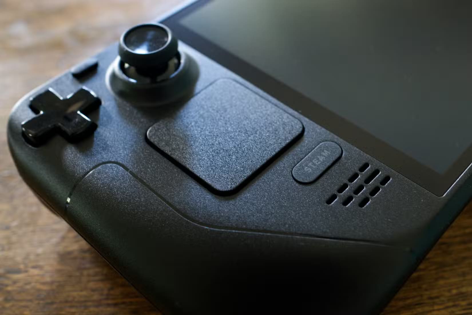 steam-deck-oled-on-a-wooden-table-with-the-steam-button-in-focus هل يعتبر Steam Deck الخيار المناسب لمحبي الألعاب بدون كمبيوتر؟