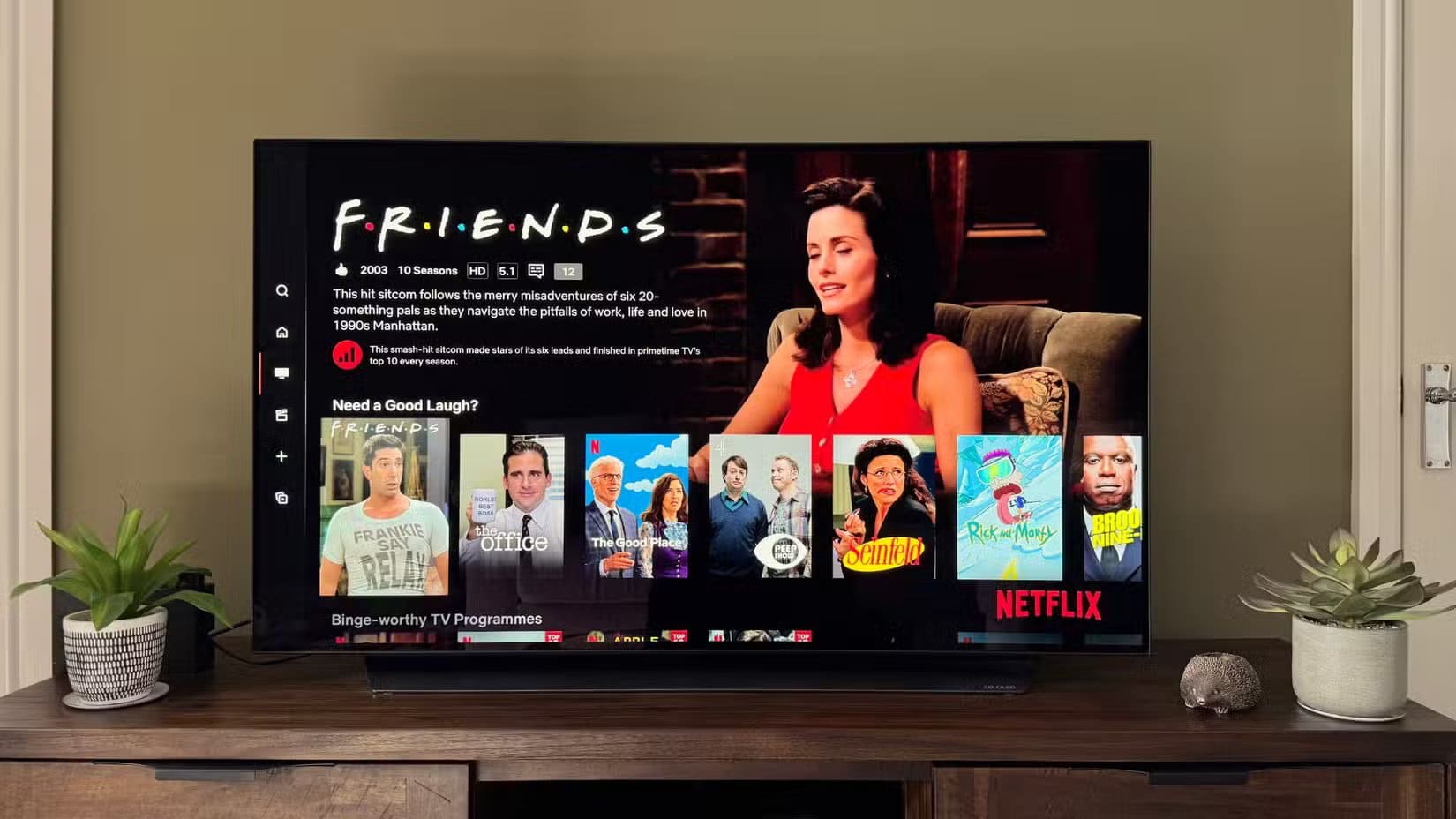 4k-tv-in-a-green-living-room-showing-friends-and-other-comfort-shows-on-netflix أشياء يجب معرفتها قبل شراء تلفزيون جديد