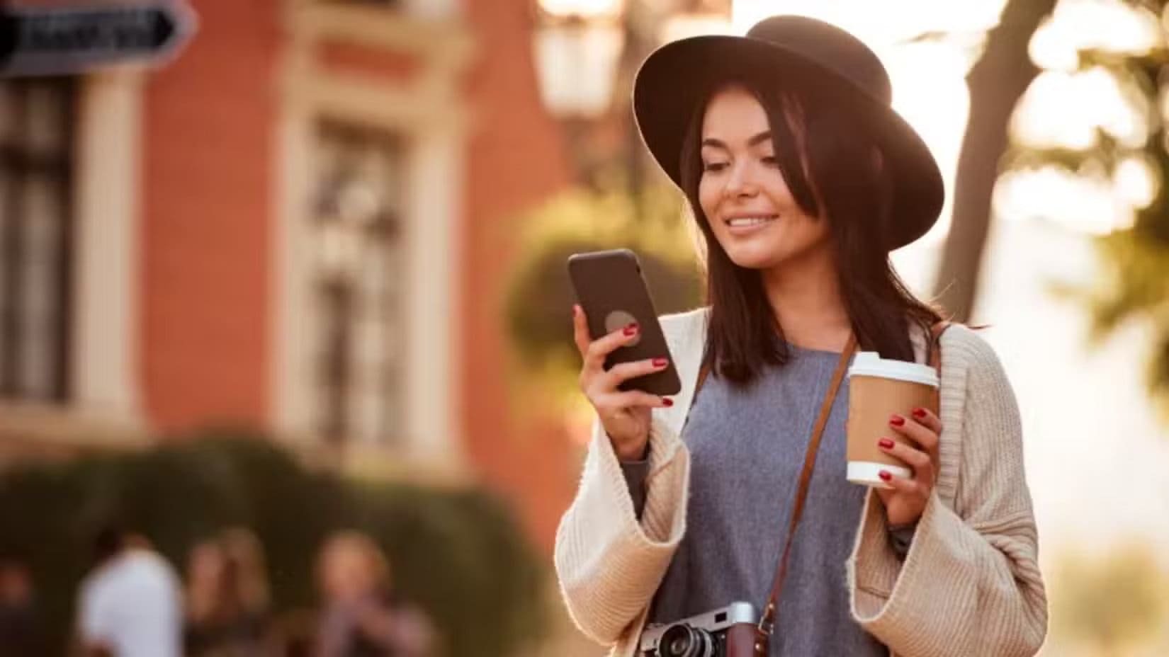 a-woman-looking-at-her-phone-while-holding-a-cup-of-coffee تطبيقات Android أثبتت فعاليتها في كسب المال بدون رأس مال