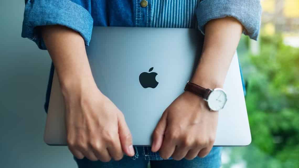 a-woman-standing-and-holding-an-apple-macbook-pro-laptop-computer أشياء يجب ألا تفعلها على جهاز Mac مطلقًا