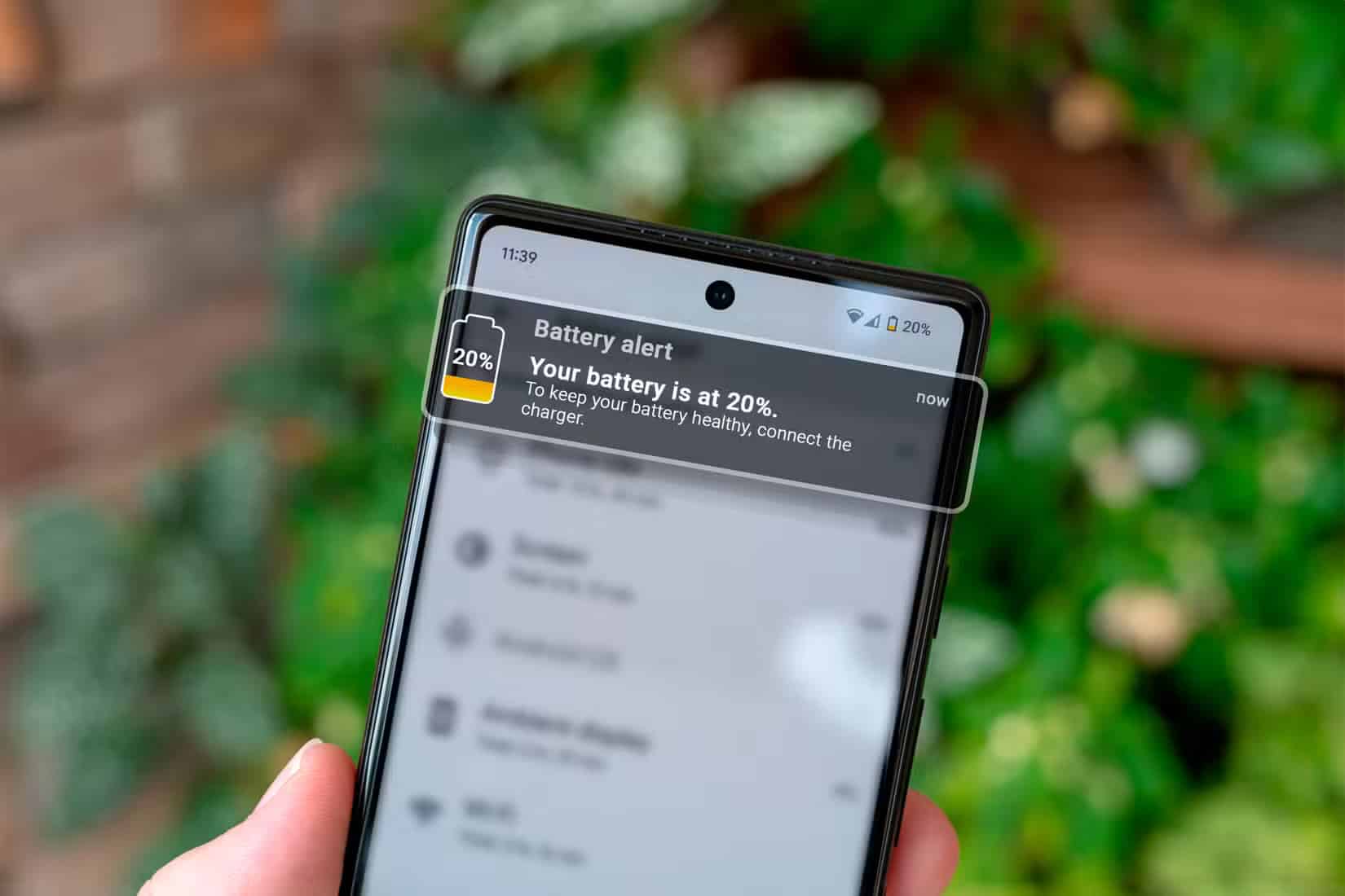 hand-holding-a-smartphone-with-a-battery-charge-notification الحقيقة الكاملة حول الشحن السريع وتأثيره على بطارية هاتفك