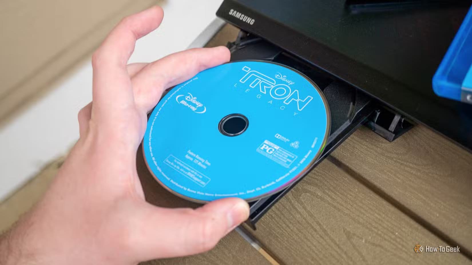person-s-hand-putting-a-blu-ray-disc-in-blu-ray-player خدمات البث ترفع جودة المشاهدة مع توسع دعم تقنية 4K