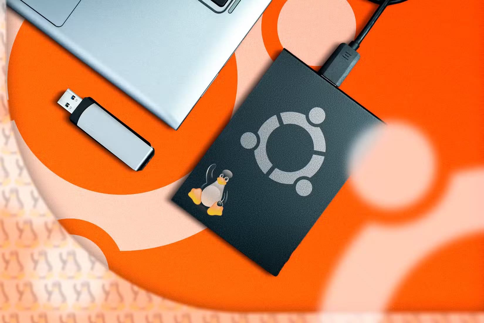 an-external-ssd-with-the-ubuntu-logo-connected-to-a-laptop-and-a-usb-flash-drive-next-to-it طريقة تشغيل أربعة أنظمة تشغيل على نفس الحاسوب بسهولة