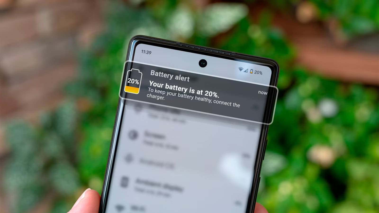 hand-holding-a-smartphone-with-a-battery-charge-notification عادات شائعة في استخدام الهاتف تُقلل من عمره دون أن تلاحظ
