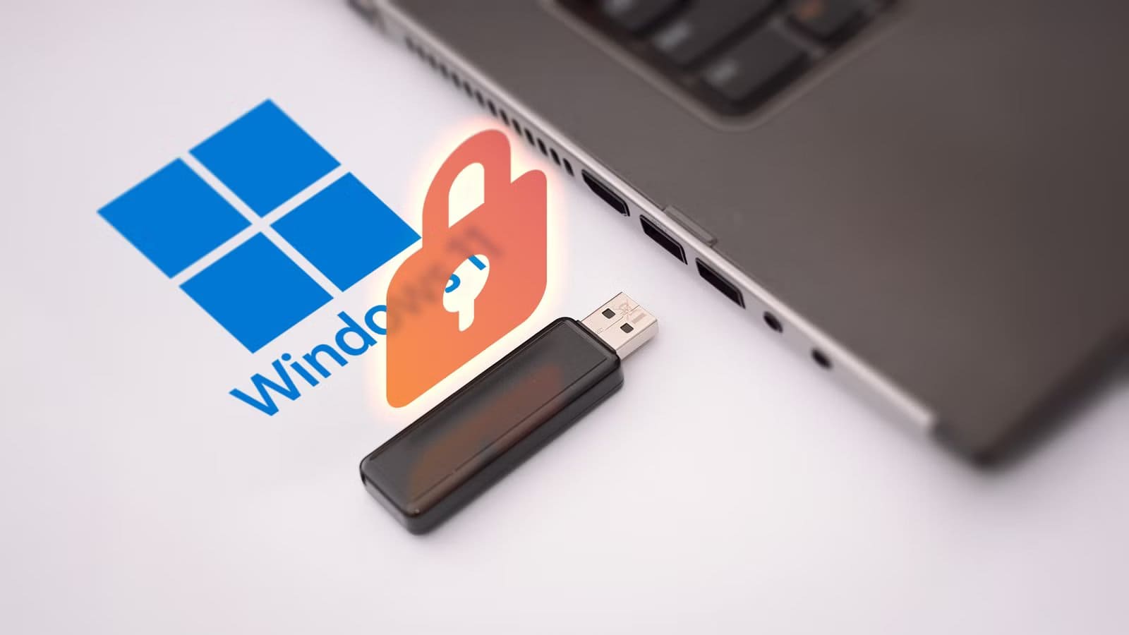 a-laptop-with-the-windows-11-logo-next-to-it-a-usb-flash-drive-and-a-padlock-above-it أفضل طريقة لإزالة برامج ويندوز 11 غير الضرورية وتثبيت برامجك المفضلة دفعة واحدة